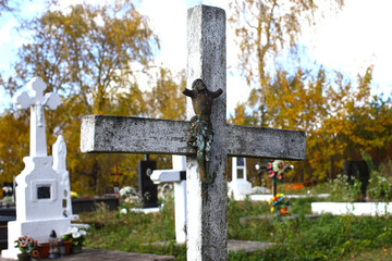 Old, rusty metal crucifix with a figure of Jesus Christ on a stone cross in a cemetery. Western Ukraine.
