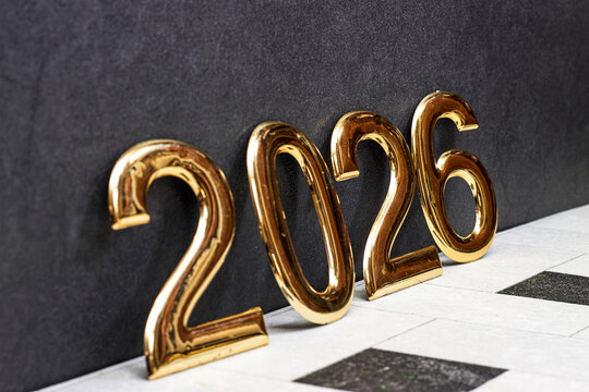 golden 2026 numerals stand on a tiled surface against a dark backdrop, creating festive New Year vibes and a premium celebratory feel suitable for events, marketing, and branding visuals