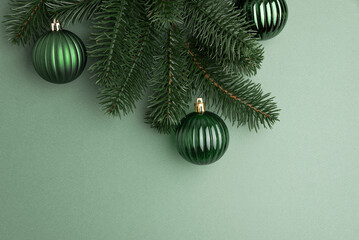 Green Christmas Ornaments Hanging on Pine Branches over Muted Green Background