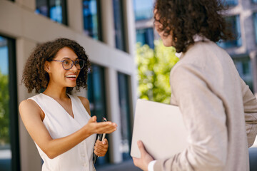 woman and man exchange greetings and contact information outside work area during networking event