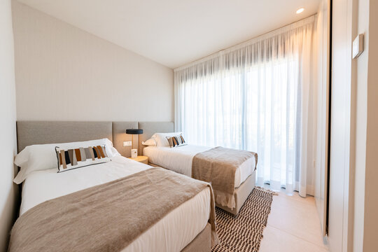Two single beds in a bright bedroom with sheer curtains in holiday home 