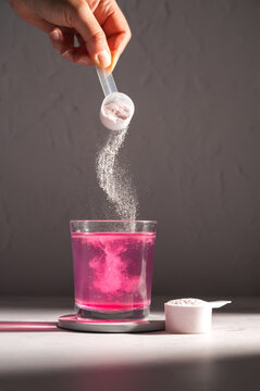 Pouring food supplement powder in glass of water. Collagen, protein powder, vitamins.