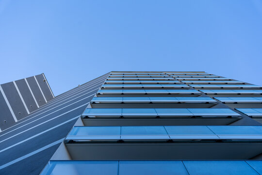 Modern High-Rise Building with Glass Facade and Balconies in Urban Cityscape
