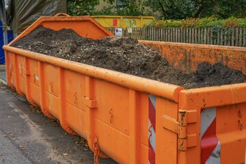 Large orange container filled with soil and gravel at a construction site.