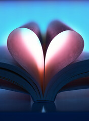 Book pages shaped into a heart with a striking blue and pink lighting. Conceptual image symbolizing love for reading, literature, imagination and creativity.