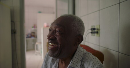 Elderly man of African descent laughing joyfully in tiled kitchen, expressing happiness and connection, candid everyday moment in a warm home setting