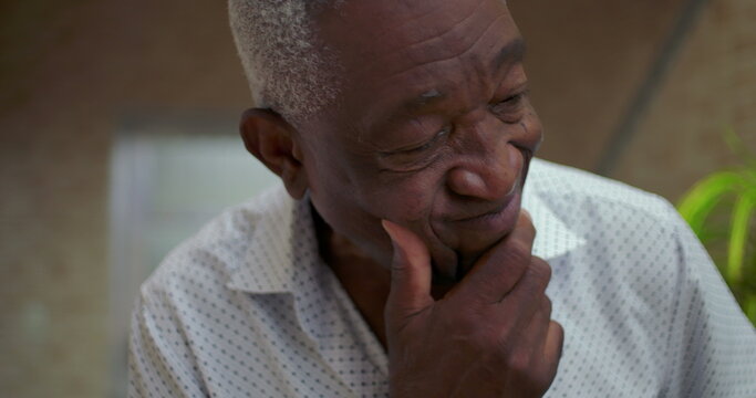 Elderly African American man resting chin on hand, showing concern with a pensive and introspective demeanor, reflecting deeply on life choices in a thoughtful moment indoors
