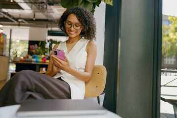 serene female enjoying digital time near sunlight, relaxed woman relaxing with device by sunny cafe