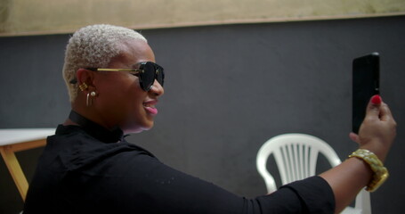 One Smiling Black woman on a video call outdoors, looking engaged and cheerful, holding a smartphone while seated in a casual setting