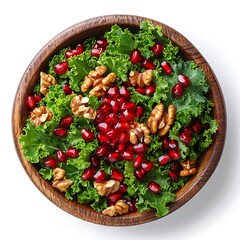Overhead view of a wooden bowl filled with salad, pomegranates, and walnuts inside it