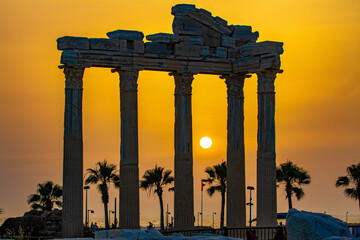 The ancient Apollo Temple at sunset, with marble columns and Corinthian capitals framing the orange...