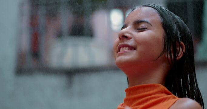 Little girl smiling with eyes closed, enjoying refreshing water spray outdoors in a vibrant community, radiating pure joy and peaceful connection with nature