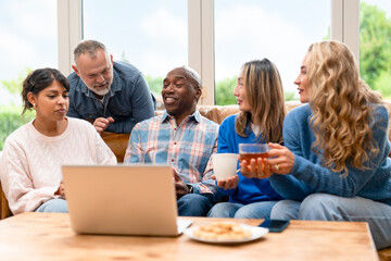 Group of friends sharing ideas and enjoying snacks while working on a laptop in a bright living room setting