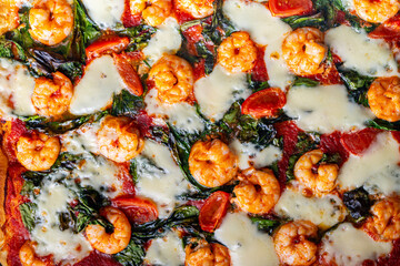 Pizza with shrimp, tomatoes and spinach, close-up. Mediterranean pizza texture background