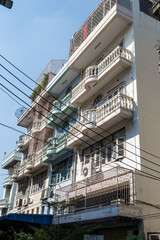 Old apartment building with balconies and cables in urban area under daylight, representing city lifestyle and local architecture concept