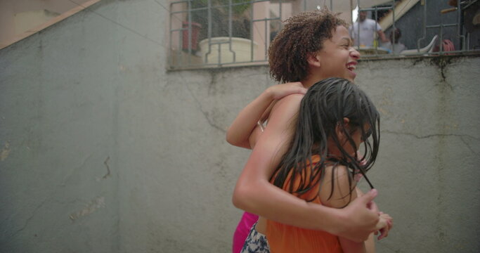 Three children laughing and hugging during backyard water play, enjoying carefree and joyful moments together in a vibrant and cheerful outdoor setting