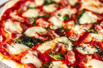 Pizza with bacon, tomatoes, spinach and cheese, close-up. Pizza textured background.
