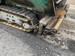 Fragment of asphalt paver or paving machine, close-up. Road works, road paving.