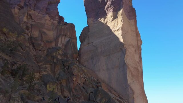 A dramatic and scenic view of the iconic Monkey Face rock pillar, a unique volcanic tuff formation, standing tall within the rugged landscape of Smith Rock State Park on a bright summer day.