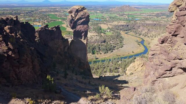 A dramatic and scenic view of the iconic Monkey Face rock pillar, a unique volcanic tuff formation, standing tall within the rugged landscape of Smith Rock State Park on a bright summer day.