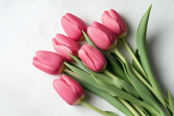 Flat lay of pink tulip bouquet with green stems on marble background