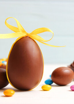 Easter composition with chocolate eggs and chocolate rabbit on wooden background. Vertical photo format