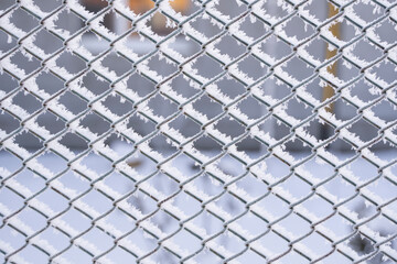 Metal chain link fence with frost in winter sunlight outdoors