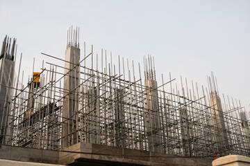 Concrete building under construction with scaffolding and steel bars