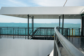 Naklejka premium Upper deck of ferry with metal railings and sea view under clear sky, modern maritime architecture