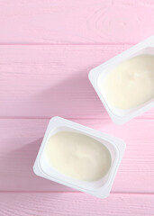 Tasty yogurt in a plastic glass on a colored table. Place to insert text.. Vertical photo format