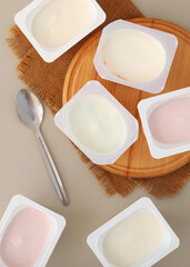 Tasty yogurt in a plastic glass on a colored table. Place to insert text.. Vertical photo format