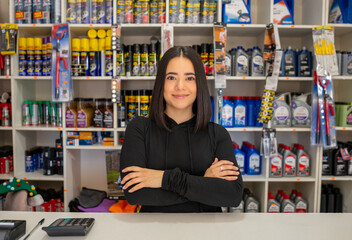 Young woman standing behind the counter of a busy automotive parts and accessories shop