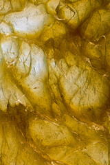 Abstract texture of yellow bearing grease illuminated from below, forming organic shapes, reflections, and patterns resembling the fluid energy of mechanics