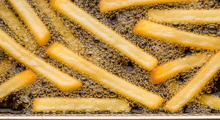 A pan of french fries is cooking in oil.