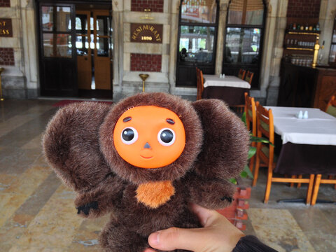 Cheburashka toy held in front of a historic restaurant in Istanbul. Nostalgia, humor, and the joyful spirit of travel and discovery.