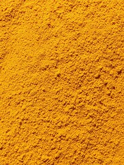 Turmeric powder creating colorful food spice background texture