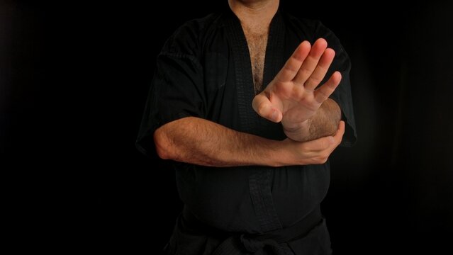 A martial artist in a black gi demonstrates a defensive blocking technique, emphasizing focus and control. A man conducts training in the Chinese martial art of Wing Chun.