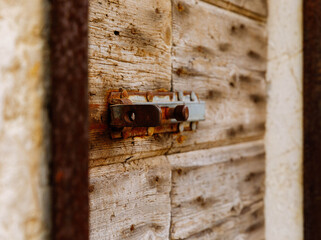 Rustic wooden door latch with weathered texture and metal bolt detail