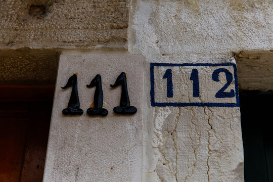 Adjacent house numbers 111 and 112 on a textured wall