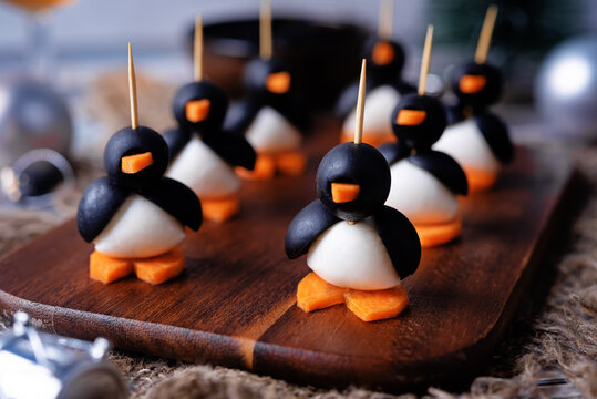 Mozzarella, carrots and black olives appetizer in the form of penguin on a cutboard for Christmas holidays