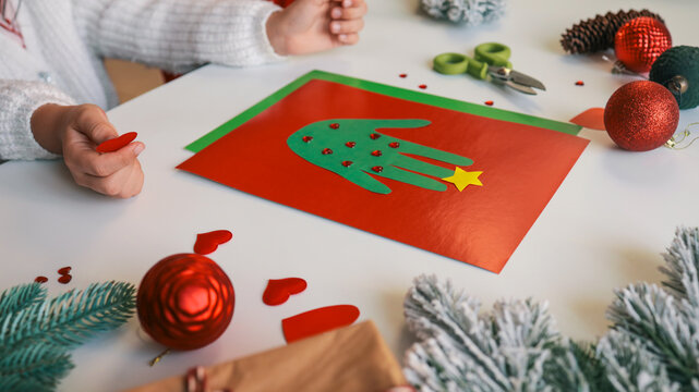 Child's handprint Christmas tree craft on red paper with decorations