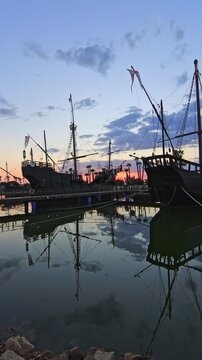 Historic replicas of Columbus' ships (Ni&ntilde;a, Pinta, Santa Maria) docked at Muelle de las Carabelas, Huelva, Spain, at twilight. Travel, history, and adventure concept.