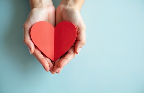 Woman hands hold red heart shape against blue background. Handmade heart shape symbolizes love care compassion. Charity donation concept. Perfect photo for healthcare social projects.
