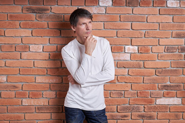 Portrait of a middle-aged European man in a white shirt near a brick wall