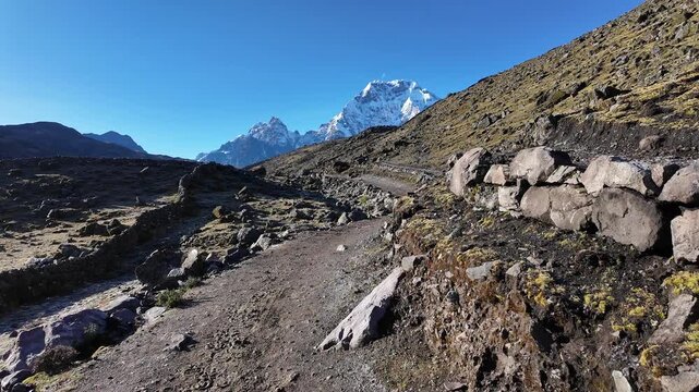 Ausangate, Peru: Point of view footage of a trekker walking on the trail to Ausangate 7 laguna hiking trail with the snowcapped mountain peak in the background in the Andes in Peru on a sunny day. 