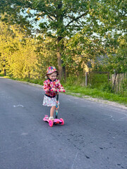 Fototapeta premium Young girl riding scooter on rural road
