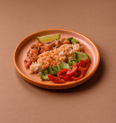 A food bowl with salmon, rice, avocado, tomatoes, and cucumbers. A salmon bowl