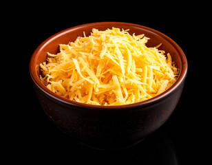 A bowl of grated cheese isolated on a black background