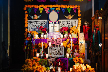 Atmospheric and close view of a traditional Mexican Day of the Dead altar, highlighting the warm light from candles and marigold flowers.
