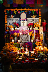 Atmospheric and close view of a traditional Mexican Day of the Dead altar, highlighting the warm light from candles and marigold flowers.